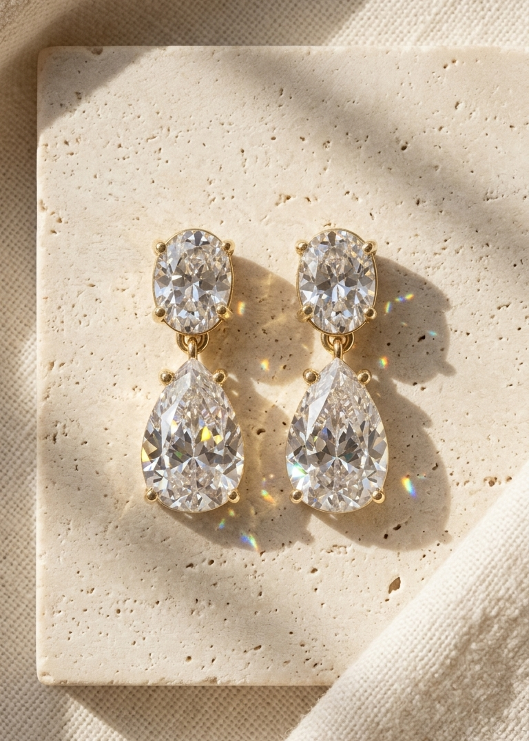 Pair of teardrop-shaped earrings on a beige stone surface