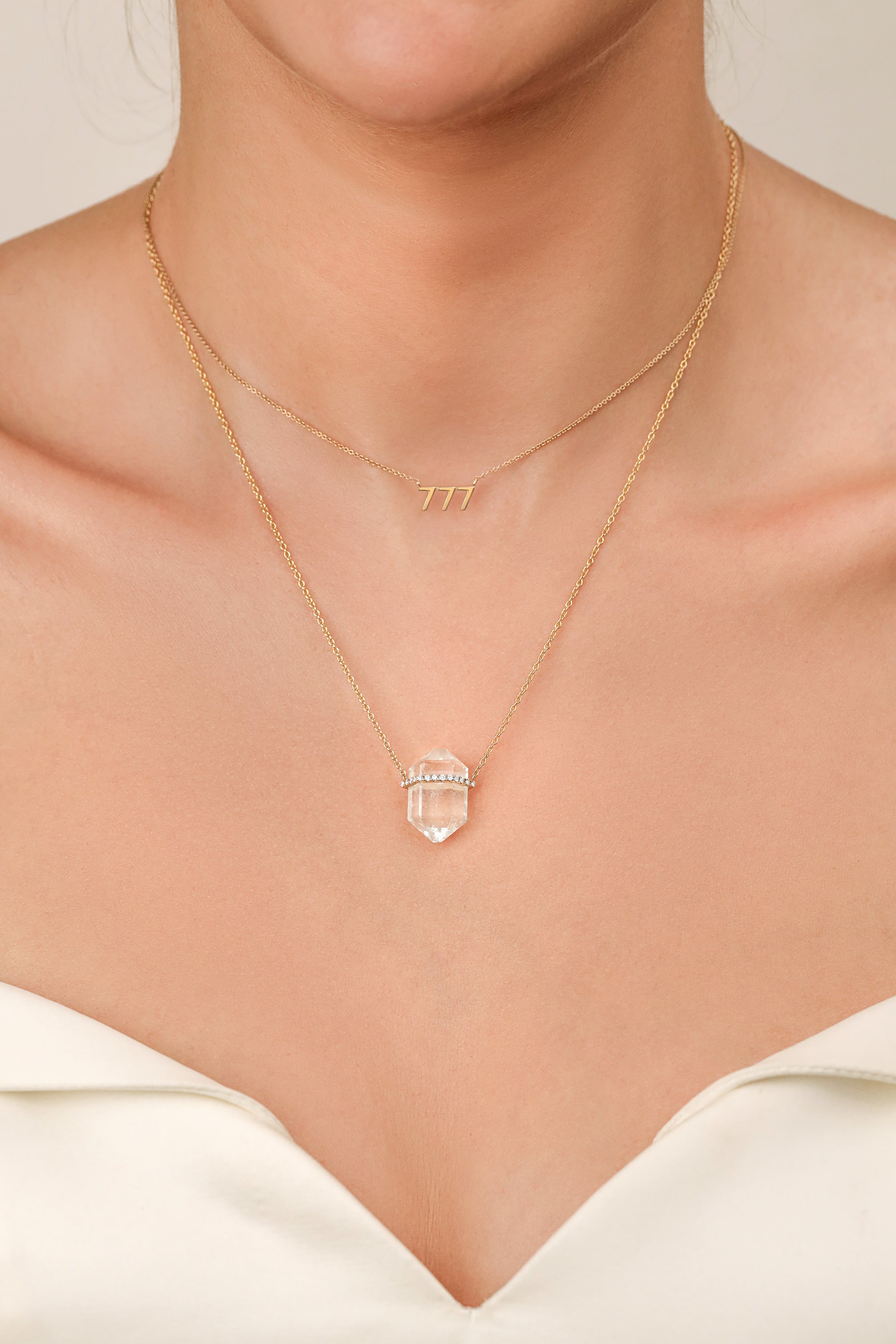 woman wearing aquamarine crystal pendant and 777 pendant by carter eve jewelry