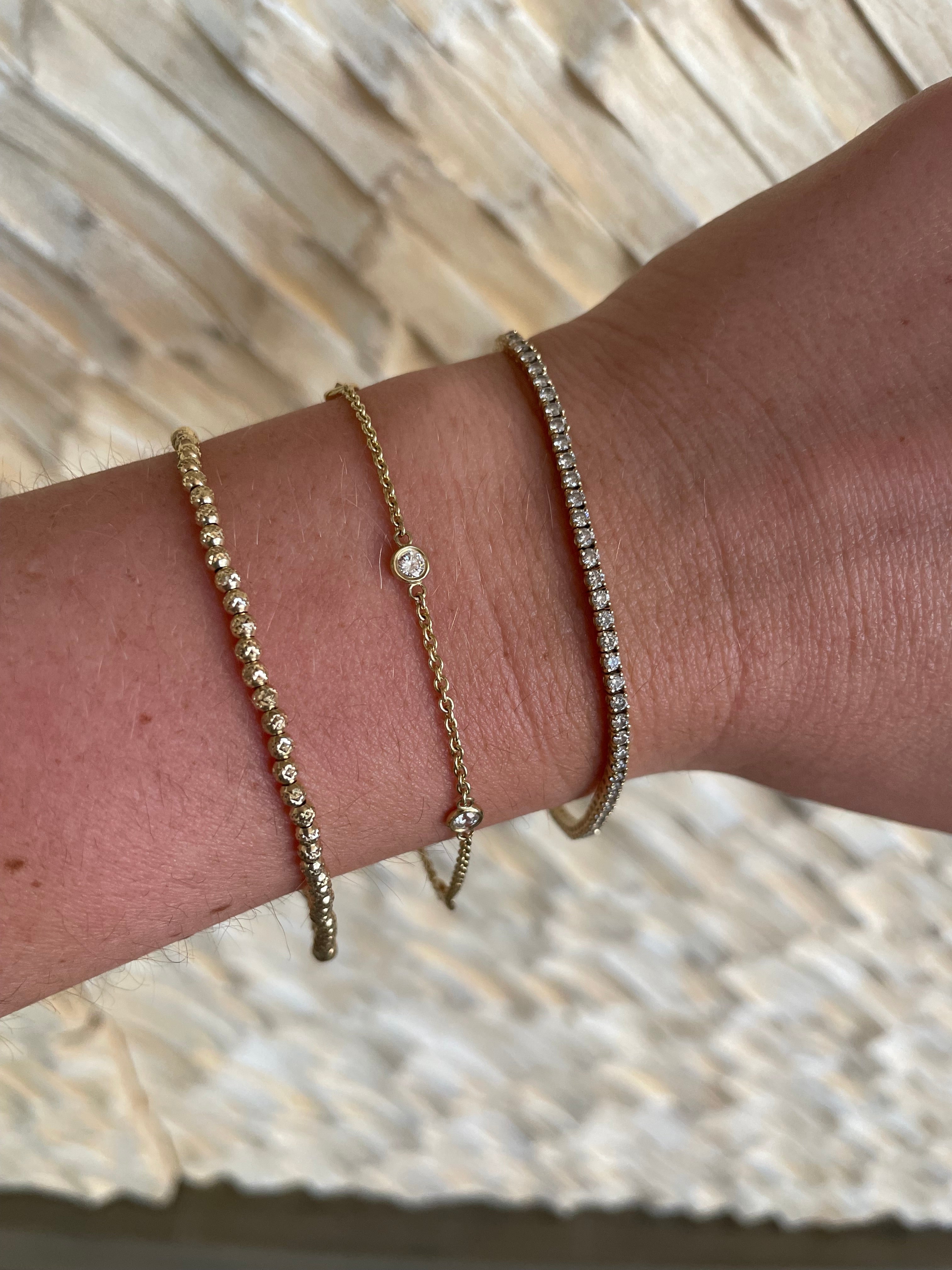 Woman wearing three gold and diamond bracelets. Elevate your every day jewelry with Carter Eve Jewelry.