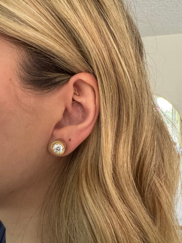 Close-up of an ear with a diamond earring and blonde hair.