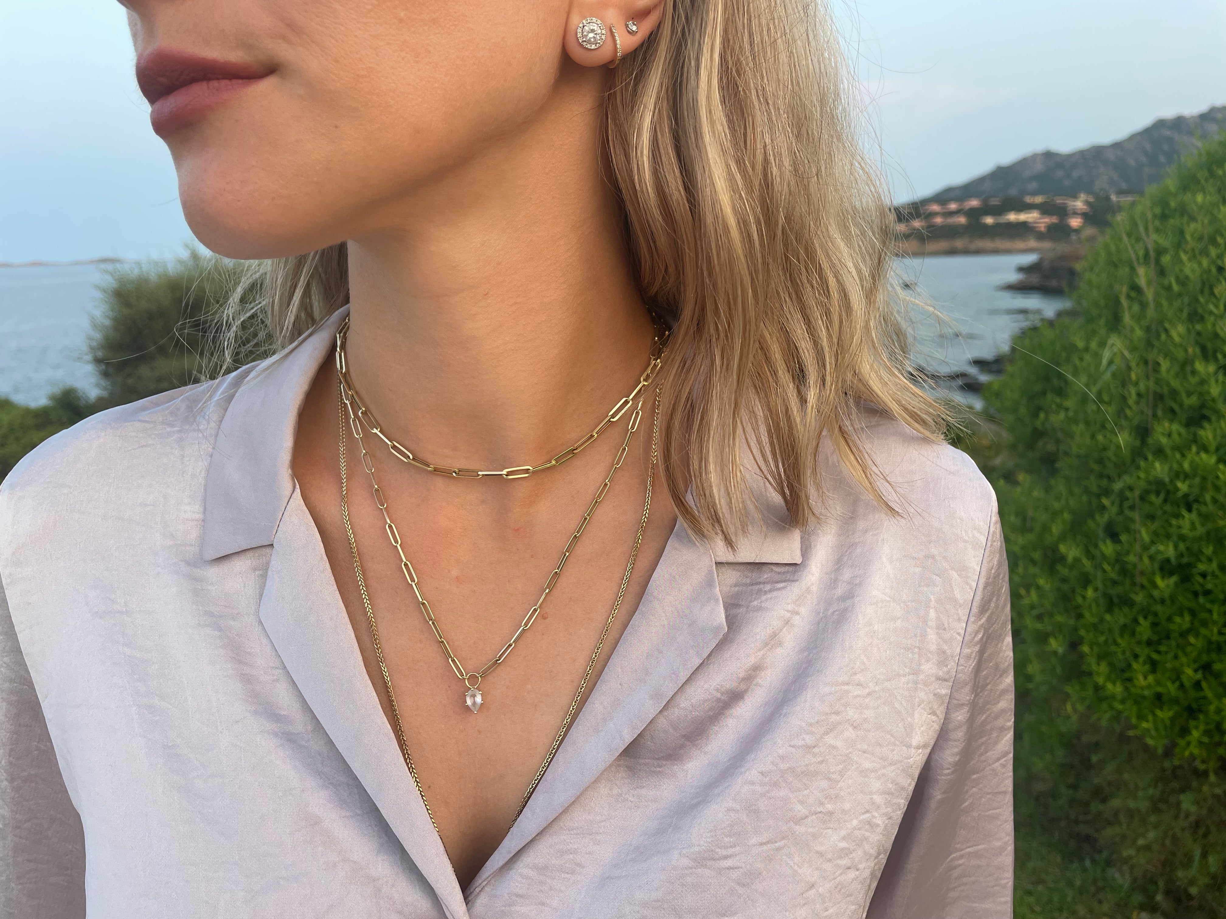 Woman wearing layered gold necklaces with a scenic background