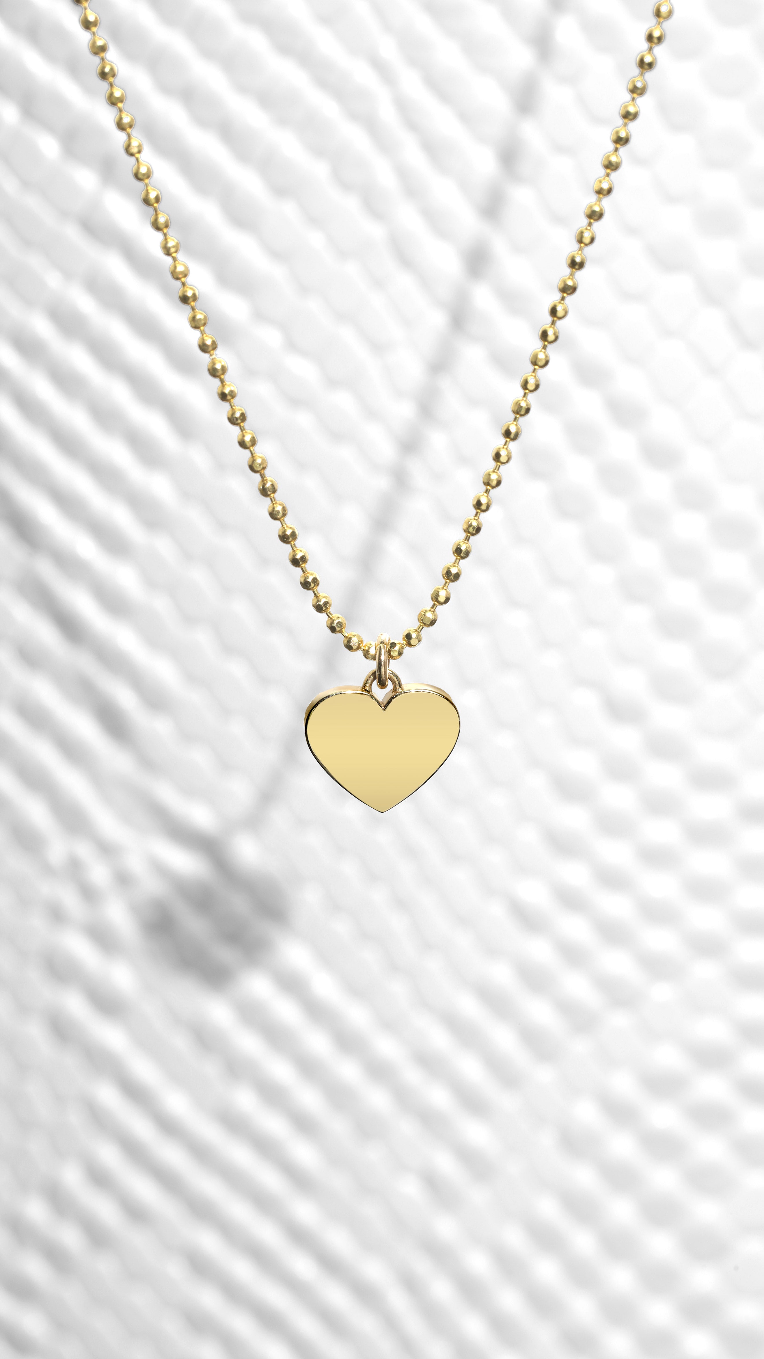 solid gold heart necklace on patterned background