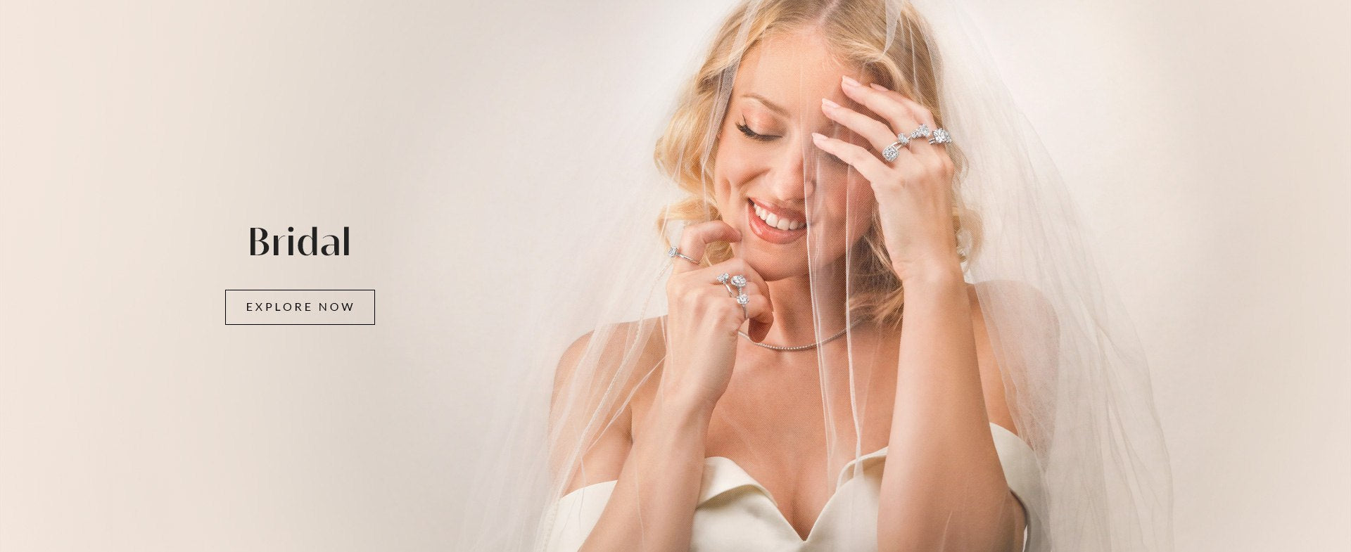 A smiling woman in a wedding dress & E and veil showcases multiple pieces of handmade designer jewelry. The word "Bridal" and a button labeled "Explore Now" are positioned to the left, inviting you to discover these unique pieces.