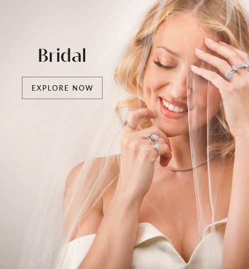 A smiling woman in a wedding dress & E and veil showcases multiple pieces of handmade designer jewelry. The word "Bridal" and a button labeled "Explore Now" are positioned to the left, inviting you to discover these unique pieces.