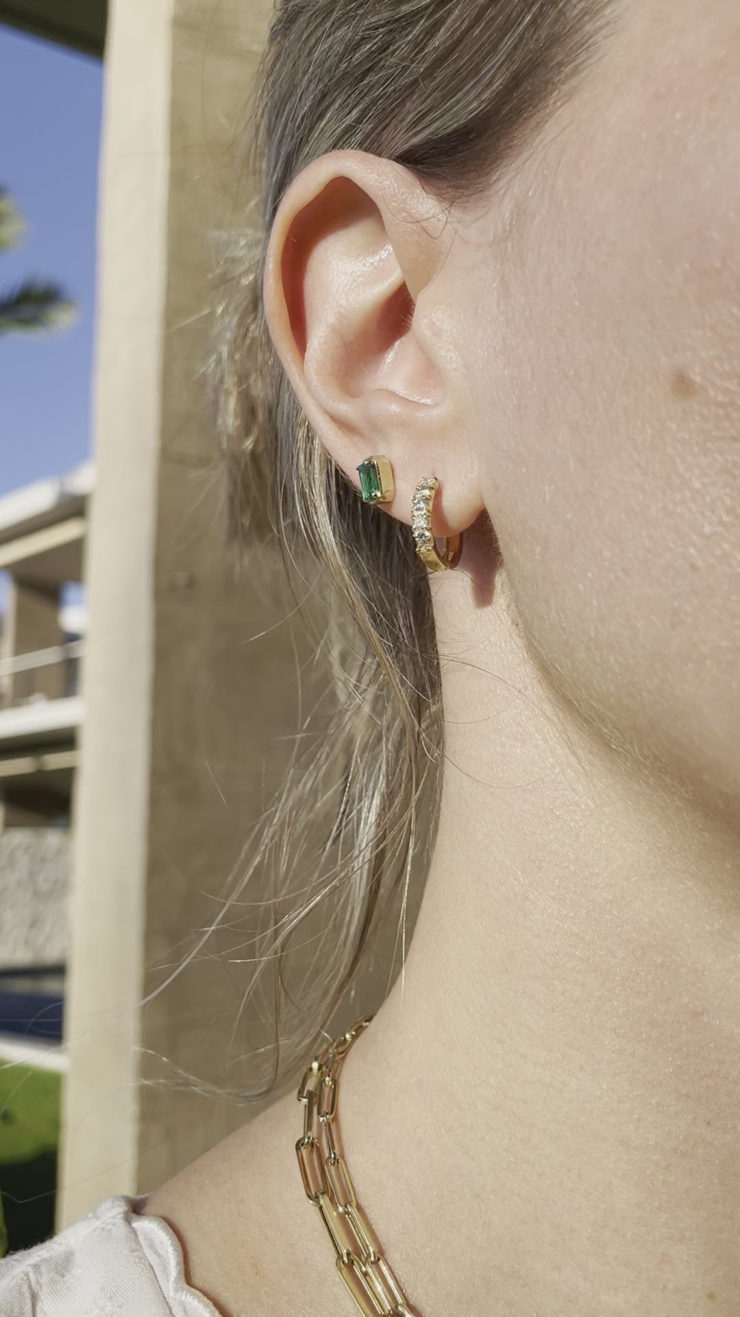 video of woman wearing emerald earrings and diamond hoop earrings